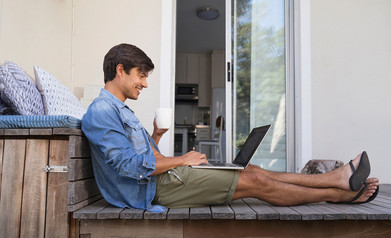 Un homme est assis sur une terrasse et se réjouit de sa feuille de présence numérique.