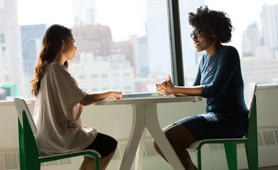 Zwei Frauen sitzend am Tisch in einem Beratungsgespräch.