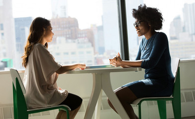 Two women sitting at a table in a counseling session.