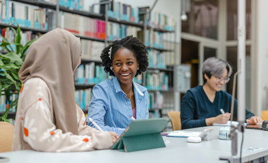 Les femmes de langue étrangère sont assises dans la bibliothèque de l'université et se réjouissent des traductions automatiques.
